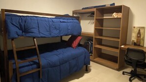 Un letto a castello con una scala, una scrivania e una sedia in una stanza con pavimento piastrellato e una luce al soffitto.