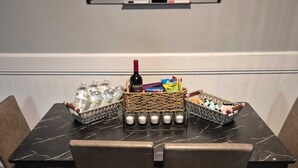 A dining table with a bottle of wine, water bottles, and baskets of snacks.