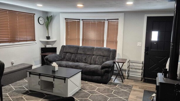 A compact living room with a gray sofa, a coffee table, and a black TV stand.