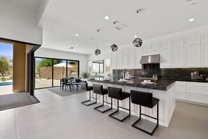 Una cocina moderna con una isla central, taburetes de bar y vistas al exterior.