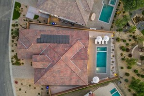 Vista aérea de un hotel con varias piscinas, un porche cubierto y un jardín ajardinado.
