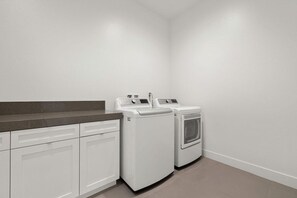 A laundry room with two white washing machines and a countertop. - Mountain Paradise: Pool & Spa Retreat (La Quinta)