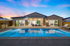 Una casa moderna con piscina, mobiliario exterior y zona de patio.