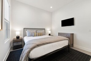 A bedroom with a bed, bedside tables, a flat-screen TV, and a window. - Mountain Paradise: Pool & Spa Retreat (La Quinta)