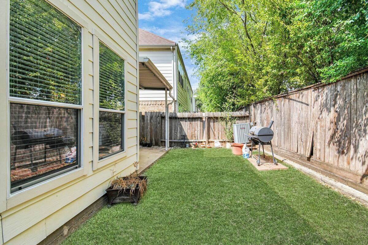 A backyard with a wooden fence, a barbecue grill, and a small garden area.
