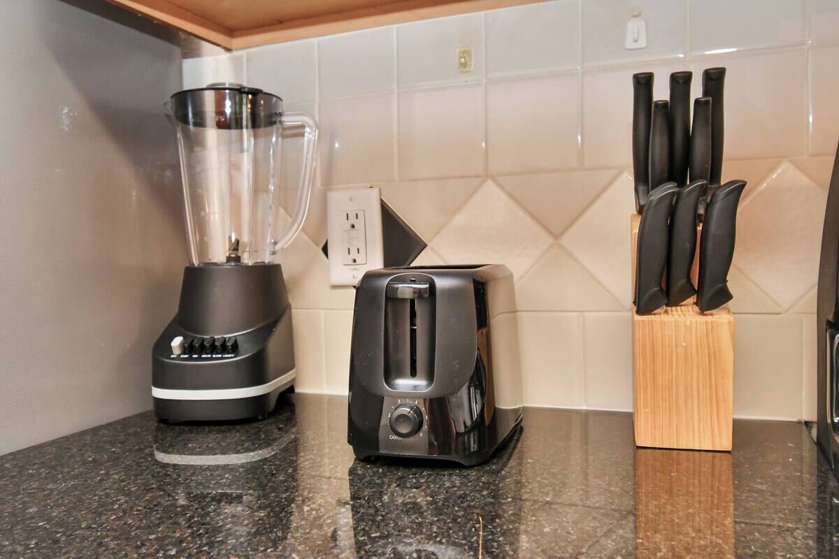 A kitchen with a blender, toaster, and knife block on the counter.