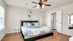 A bedroom with a bed, a ceiling fan, a window, and a door.
