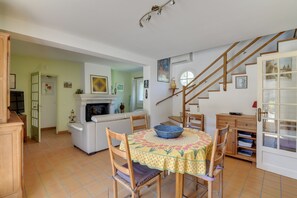 Un comedor con una mesa redonda, sillas, un bol y una chimenea.
