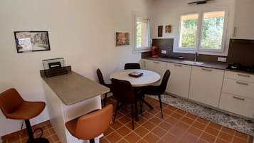 Une cuisine compacte comprenant un coin repas, un petit réfrigérateur et une machine à café.