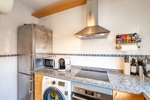 A modern kitchen with stainless steel appliances, a built-in washing machine, and a countertop with a coffee maker and toaster.