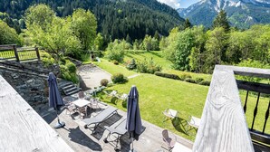 Une terrasse dotée de mobilier d’extérieur, d’un mur en pierre et offrant une vue sur un paysage montagneux.