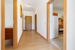 Ein Flur mit Holzboden, einer Tür am Ende und einem durchgehenden Durchblick in den Küchenbereich.