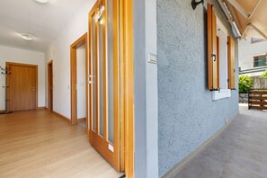 A hallway with wooden doors, a blue textured wall, and a tiled floor.