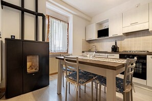 A modern kitchen with a dining table, chairs, a refrigerator, a stove, and cabinets.