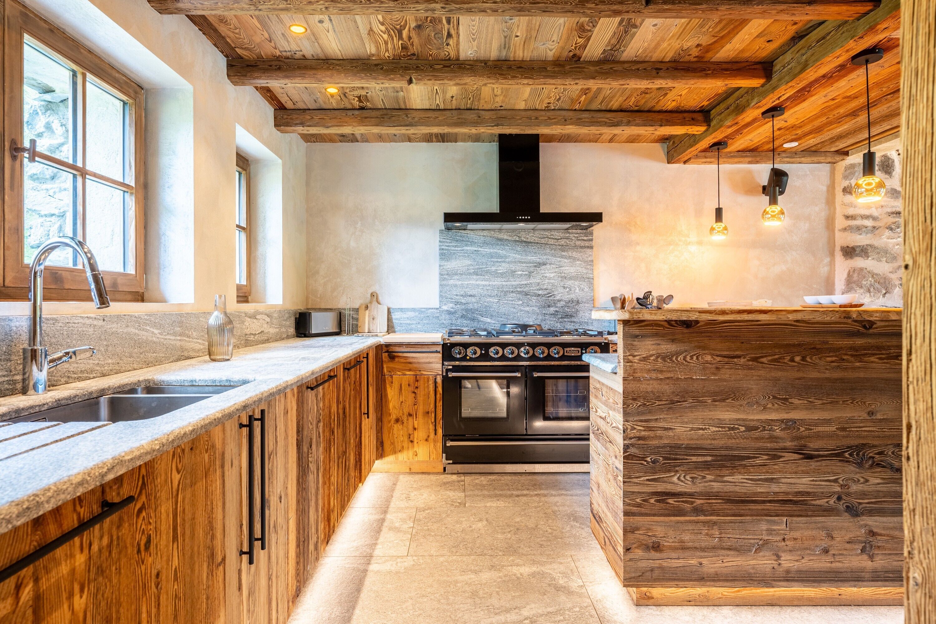 A kitchen with wooden cabinetry, a stainless steel sink, a built-in oven, and a stone backsplash.