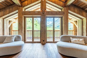 Un interior de madera con un gran ventanal, dos sofás y techo de madera.