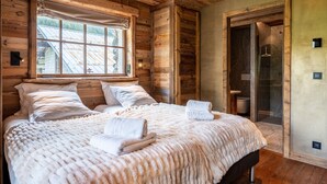 Une chambre aux murs lambrissés, avec un grand lit, une fenêtre et un espace douche.
