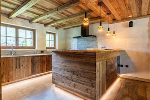 Una cocina con armarios de madera, una isla central, luces colgantes y un salpicadero de piedra.