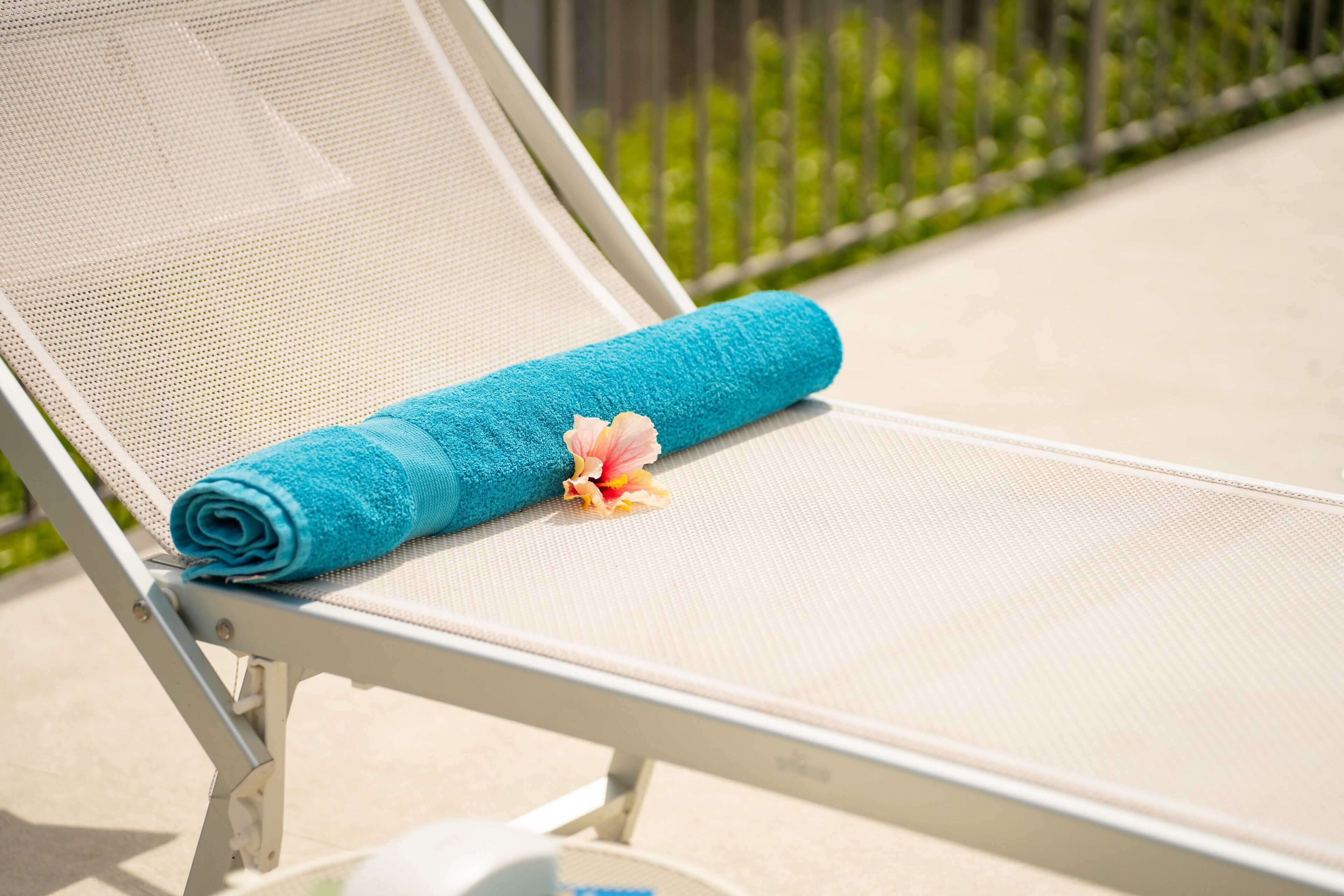 Una silla de descanso con una toalla azul y una flor.