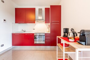 Uma cozinha moderna com armários vermelhos, eletrodomésticos de aço inoxidável e bancada de madeira.