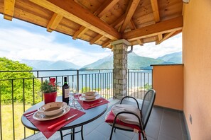 Un balcon avec une table dressée pour le dîner, une plante en pot et une bouteille de vin.