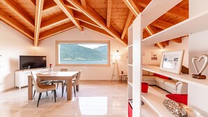 Een modern interieur met een eethoek, een televisie, een groot raam met uitzicht op de bergen en houten balken in het plafond.