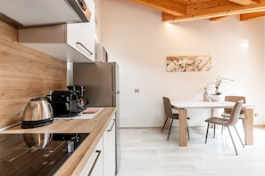 Une cuisine moderne équipée d’un four encastré, d’une machine à café et d’un coin repas avec une table et des chaises.