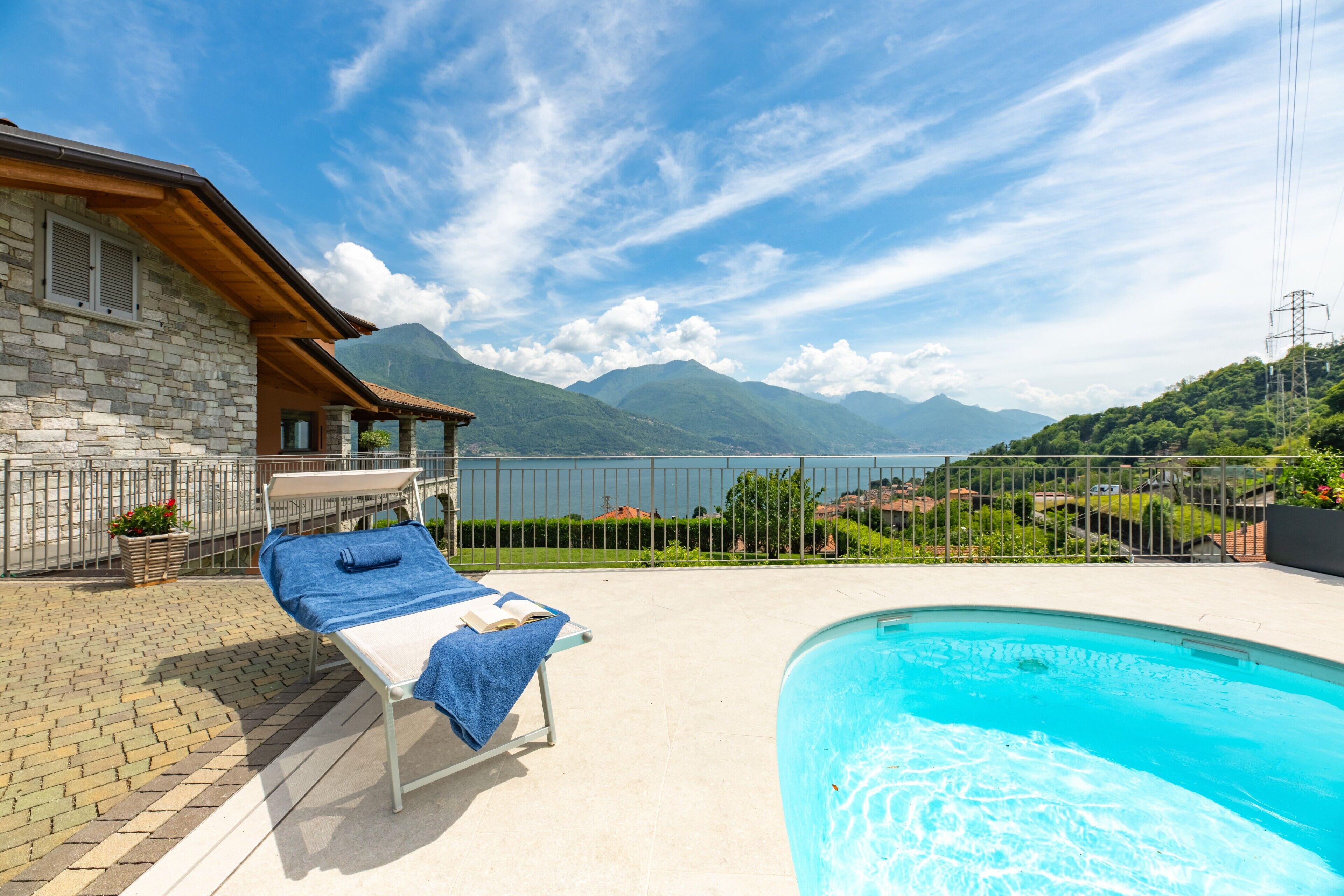A pool area with lounge chairs and a view of mountains.