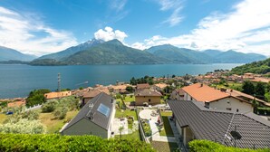 A residential area with houses, a lake, and mountains in the background. - Room 'Elena' with shared pool, Wi-Fi and air conditioning (Musso)