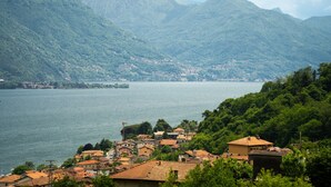 A lakeside village with terraced houses, a mountain backdrop, and a view of the lake. - Room 'Elena' with shared pool, Wi-Fi and air conditioning (Musso)