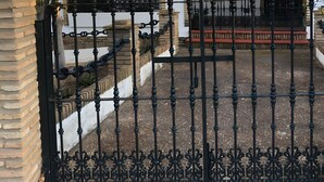 A gated courtyard with a brick wall, a wrought iron gate, and a building with arched windows and a tiled roof. - Chalet El Paraíso with sea views, private terrace, and Wi-Fi (Laguna del Portil/Huelva)