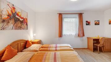 Ein Schlafzimmer mit einem Bett, einem Schreibtisch und einem Fenster mit Vorhängen.
