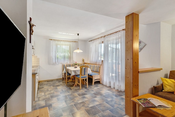 A dining area with a table and chairs, a bench, and a wooden column.