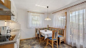 A kitchen with a built-in stove, a sink, and a dining area with a table and benches. - Apartment 'Buche' with Mountain View, Private Garden and Wi-Fi (Ridanna)