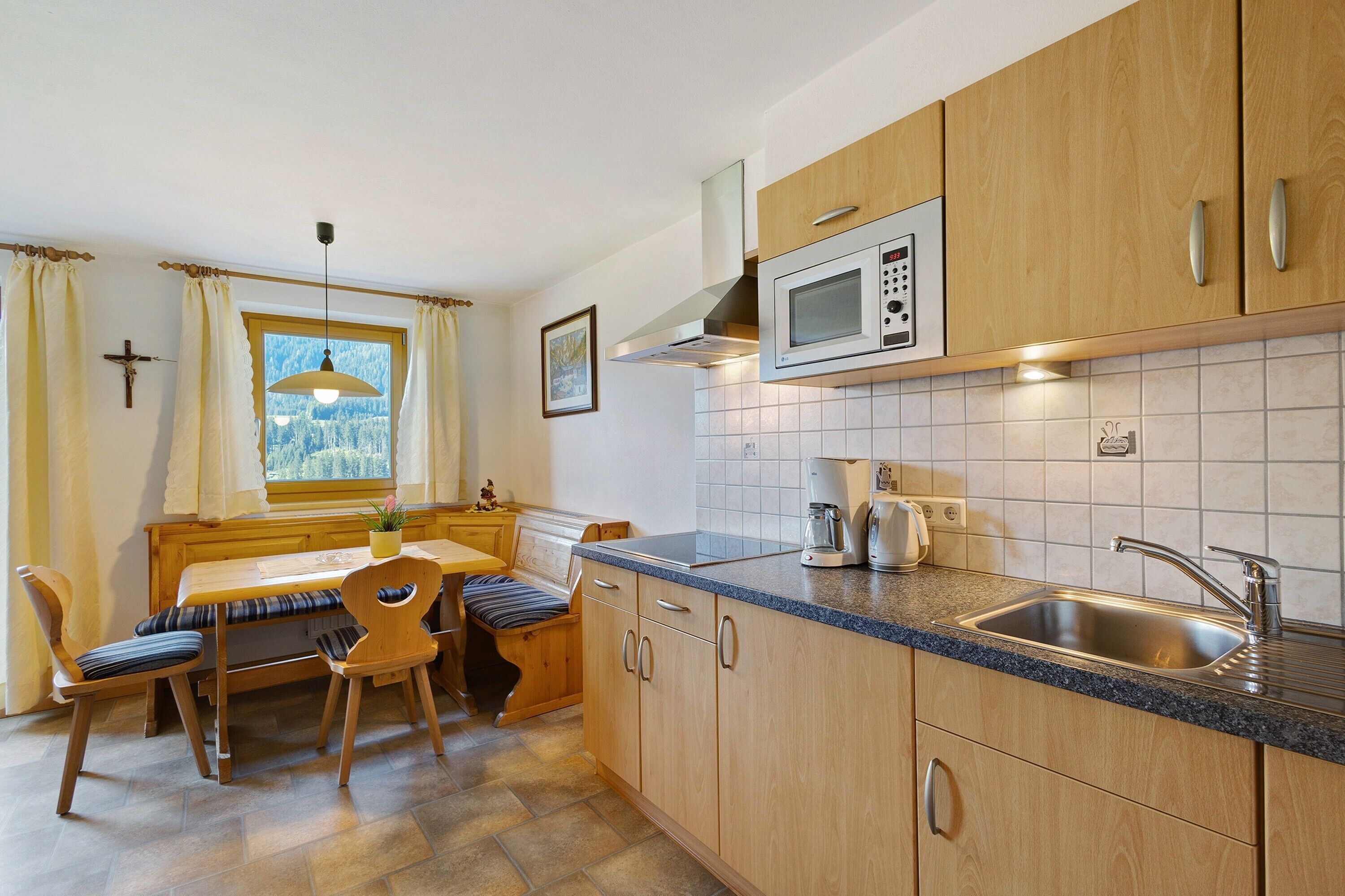 A kitchen with wooden cabinets, a built-in microwave, a sink, and a dining area with a table and chairs.
