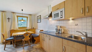 A kitchen with wooden cabinets, a built-in microwave, a sink, and a dining area with a table and chairs.