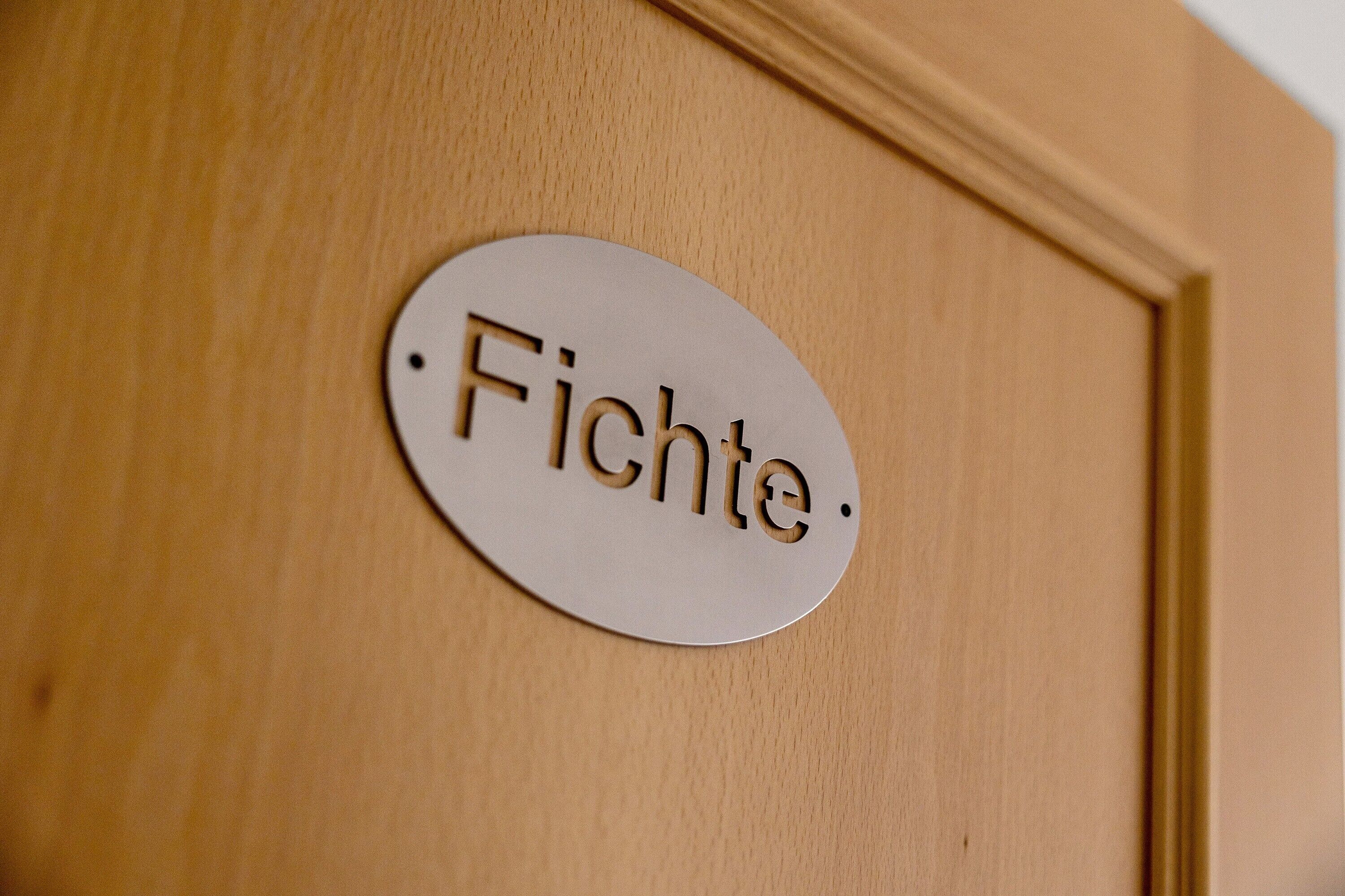 Une porte en bois sur laquelle est fixée une plaque ronde portant l’inscription « Fichte ».
