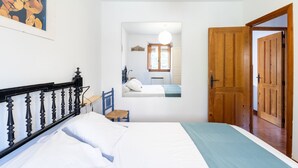 Une chambre à coucher avec un lit, une chaise, une porte en bois et un tableau accroché au mur.
