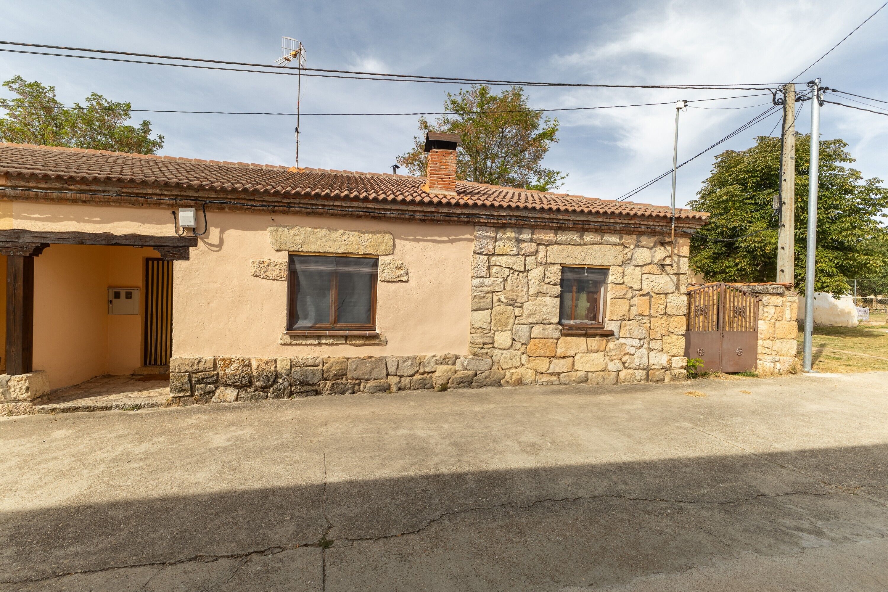 Une maison de plain-pied avec une façade en pierre, un toit en tuiles et un petit porche.