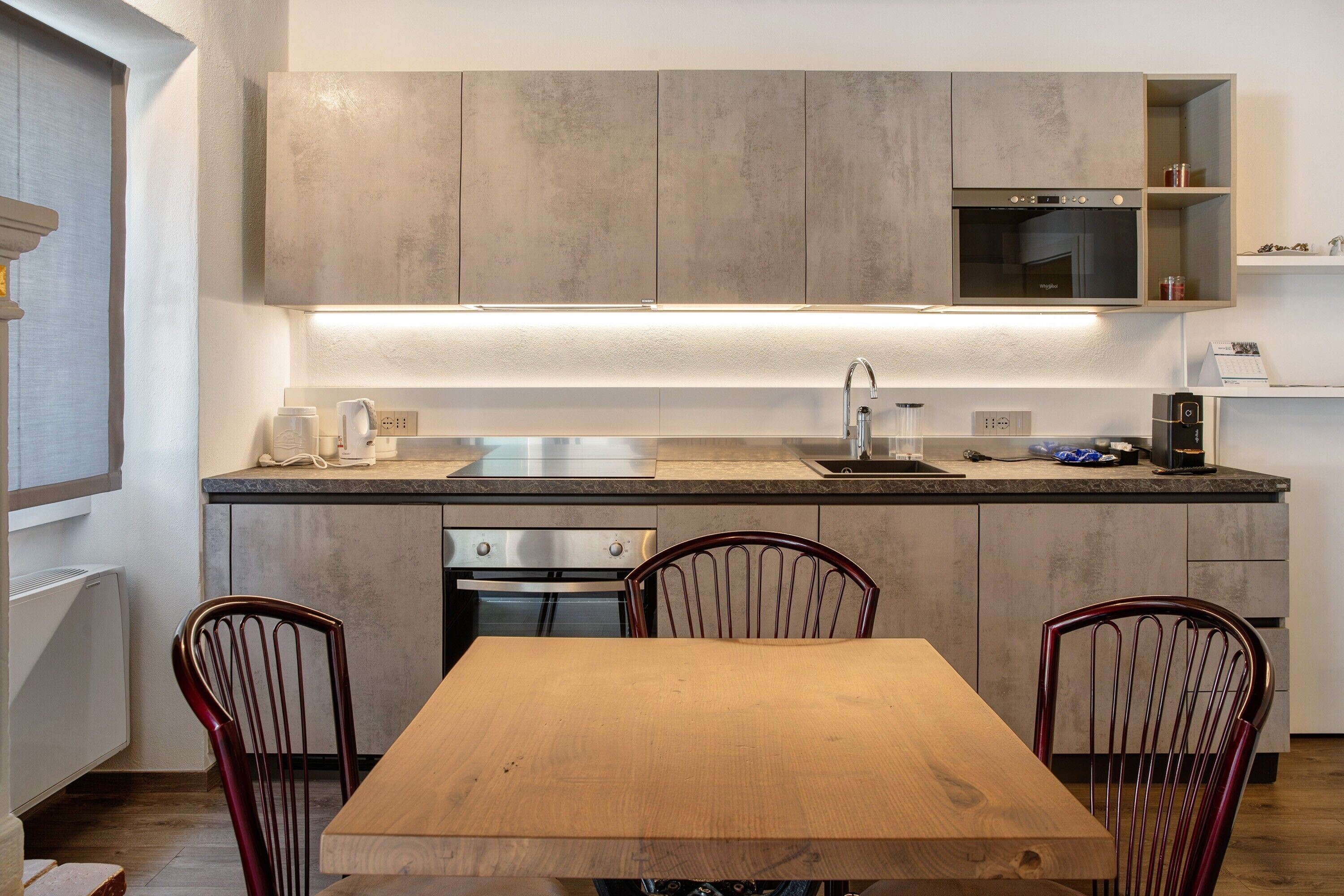 Une cuisine moderne dotée d’appareils électroménagers intégrés, d’une table à manger en bois et de deux chaises.