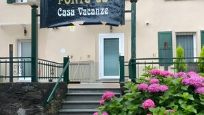 Rakennuksessa on kyltti, jossa lukee ”PORTO 03 Casa Vacanze”, ja portaikko johtaa sisäänkäyntiin.