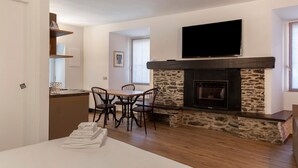 A modern living room with a fireplace, a flat-screen TV mounted above it, and a dining area with a table and chairs. - Holiday Home 'Rosso' with Mountain View, Wi-Fi and Air Conditioning (Albosaggia)