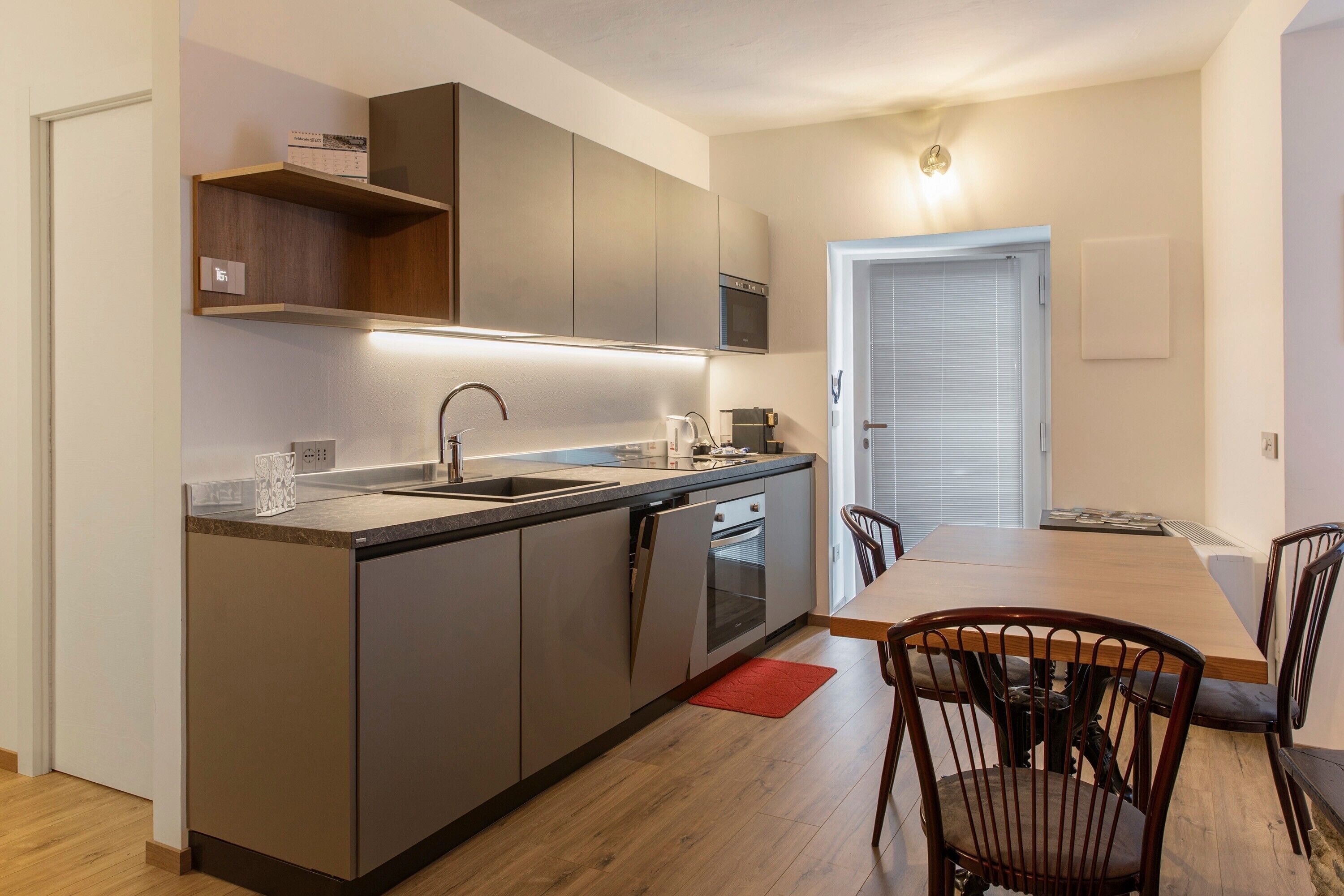 Une cuisine moderne dotée d’un îlot central, d’appareils électroménagers intégrés et d’un coin repas avec une table et des chaises en bois.