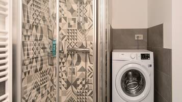 Une salle de bain avec des carreaux décorés, un lave-linge et un porte-serviettes.