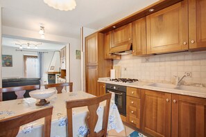 Eine Küche mit Holzausstattung, einem Gasherd, einem Spülbecken und einem Essbereich mit Tisch und Stühlen.