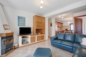 Ein Wohnzimmer mit Fernseher, Holzschränken, einem blauen Sofa und einem Kamin.