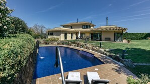 A house with a swimming pool, a patio with lounge chairs, and a well-maintained lawn. - Villa 'Luxury Golf Villa Torremirona' with Mountain View, Wi-Fi and Air Conditioning (Navata)