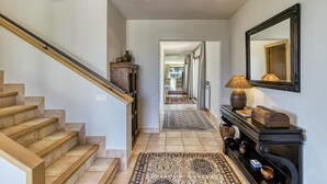 A staircase leading to a hallway with a wooden console table, a mirror, and a lamp. - Villa 'Luxury Golf Villa Torremirona' with Mountain View, Wi-Fi and Air Conditioning (Navata)