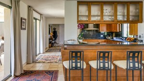 A modern kitchen with a central island, bar stools, and wooden cabinets. - Villa 'Luxury Golf Villa Torremirona' with Mountain View, Wi-Fi and Air Conditioning (Navata)