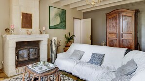 A living room with a fireplace, a sofa, a chandelier, and a large wooden cabinet.
